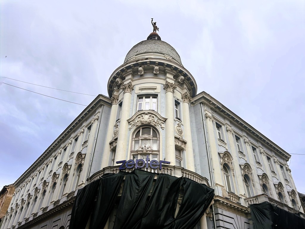 A historical building with a dome, featuring ornate architectural details and covered scaffolding, displaying a sign with the word 'zeppier'.