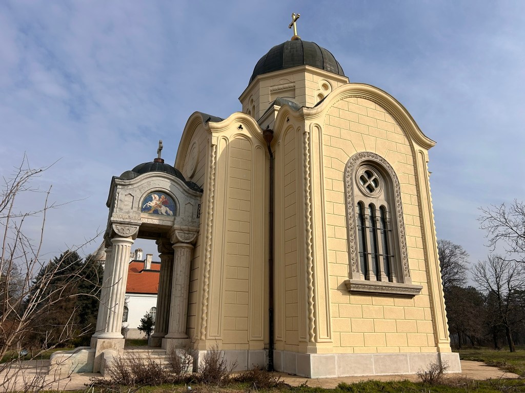 A side view of a yellow church with a rounded dome, featuring decorative elements and an archway with columns.