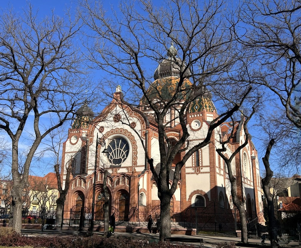 Historic building with ornate architecture, surrounded by leafless trees against a clear blue sky.