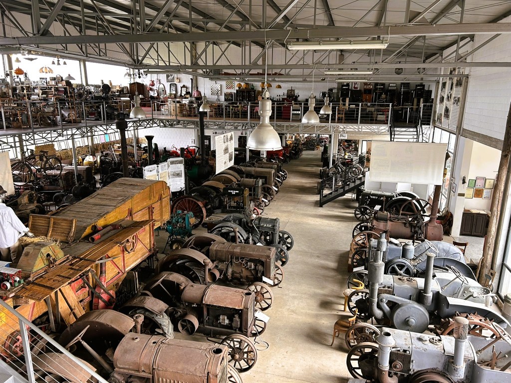 A wide view of an indoor museum showcasing various vintage machines and steam engines, with multiple levels of exhibits and displays surrounded by antique furniture.