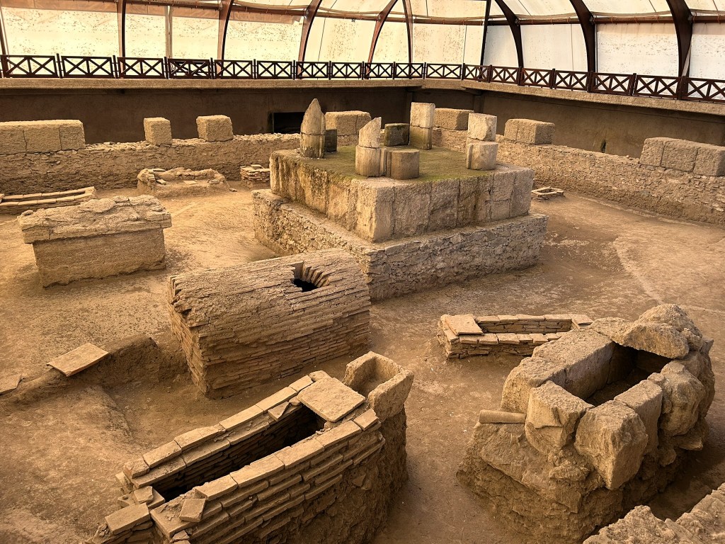 An archaeological site featuring ancient stone structures and tombs within a protective dome.