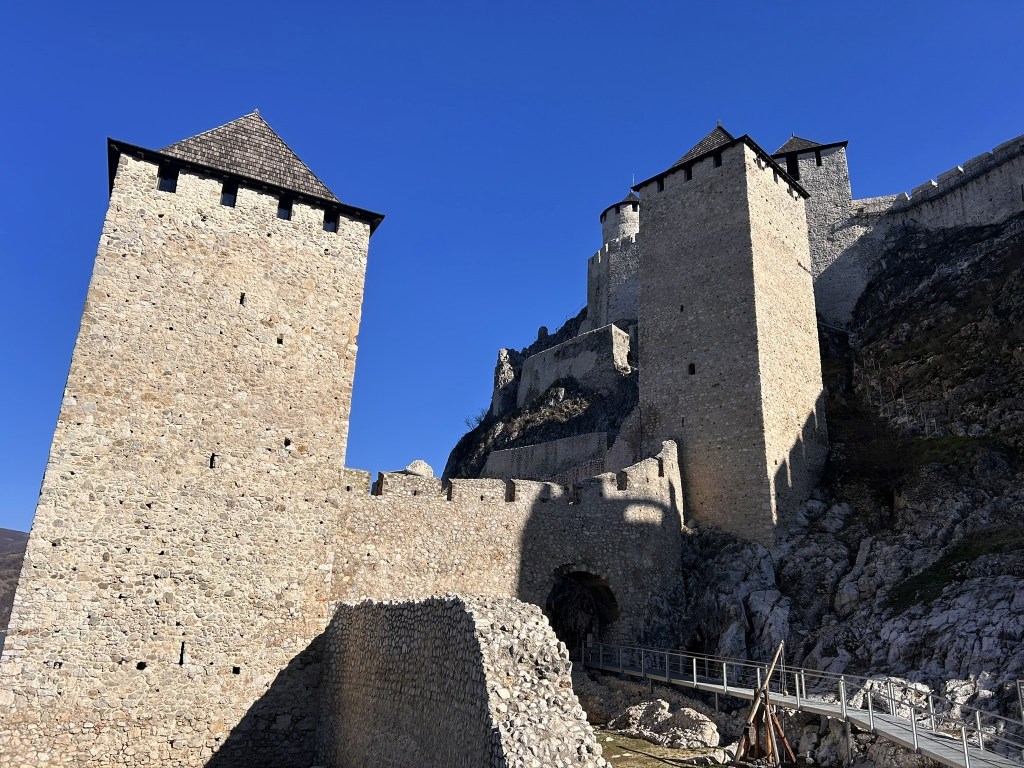 A medieval stone castle with two prominent towers under a clear blue sky.