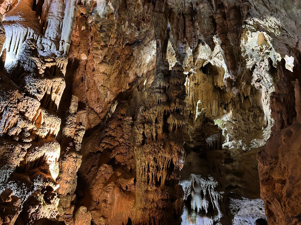 Interior view of a cave featuring dramatic rock formations and stalactites illuminated by soft lighting.