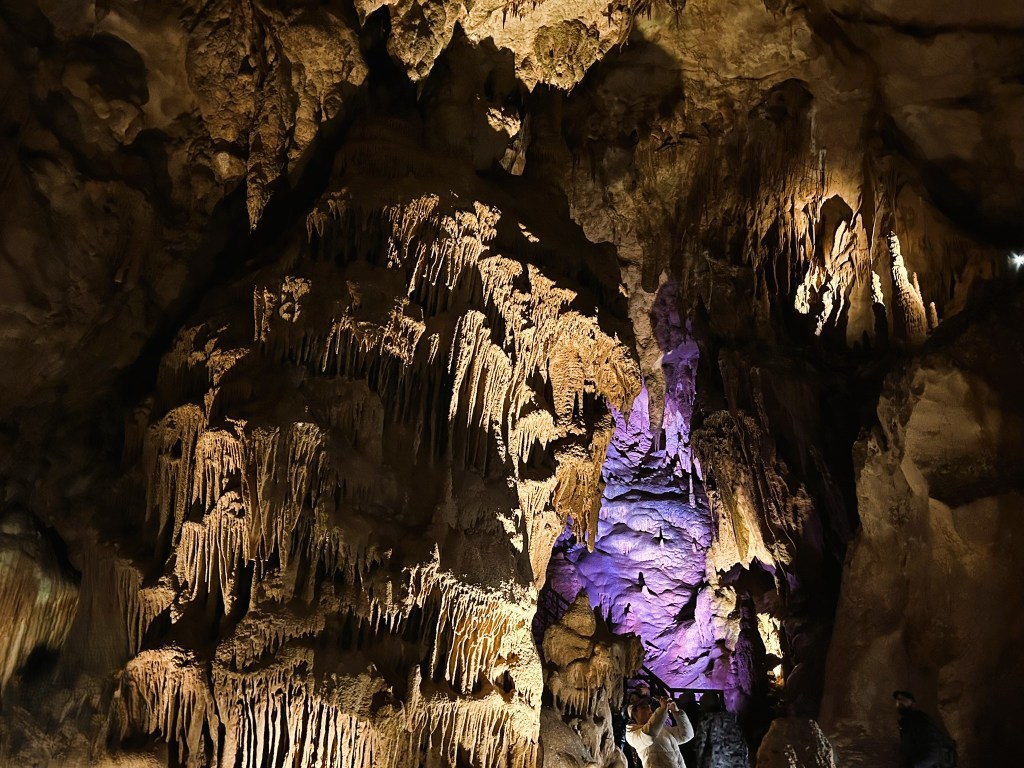An intricate cave interior featuring stunning stalactites and stalagmites, illuminated by soft lighting, showcasing natural rock formations.