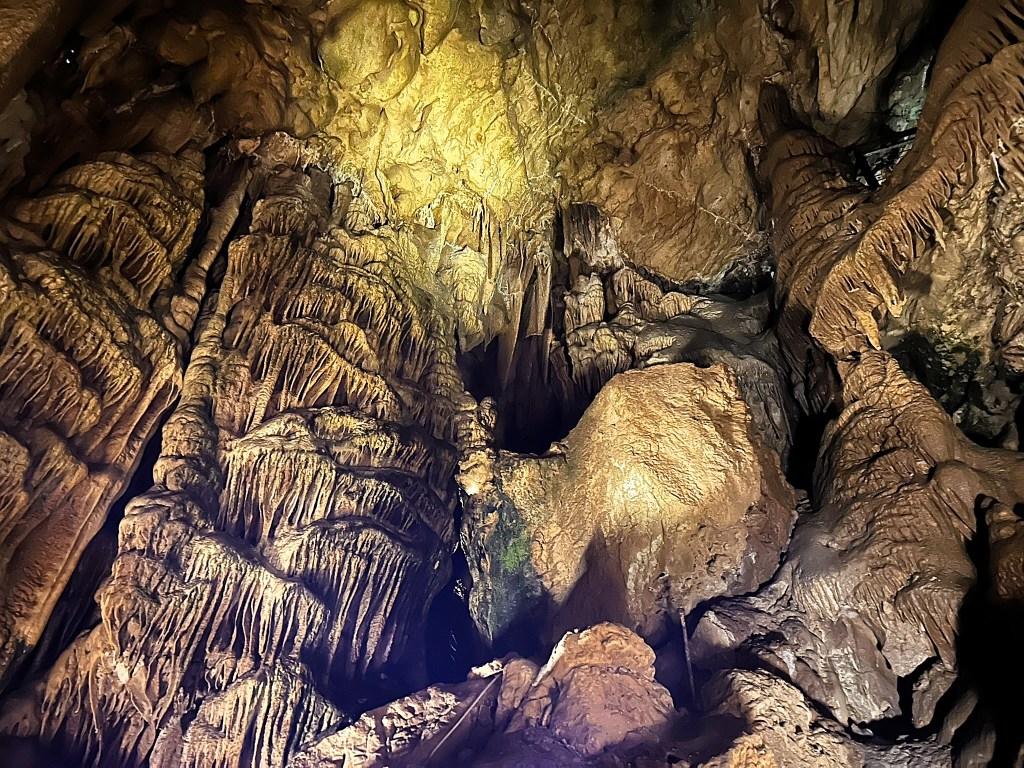 Interior of a cave showcasing impressive rock formations and stalactites illuminated by soft lighting.