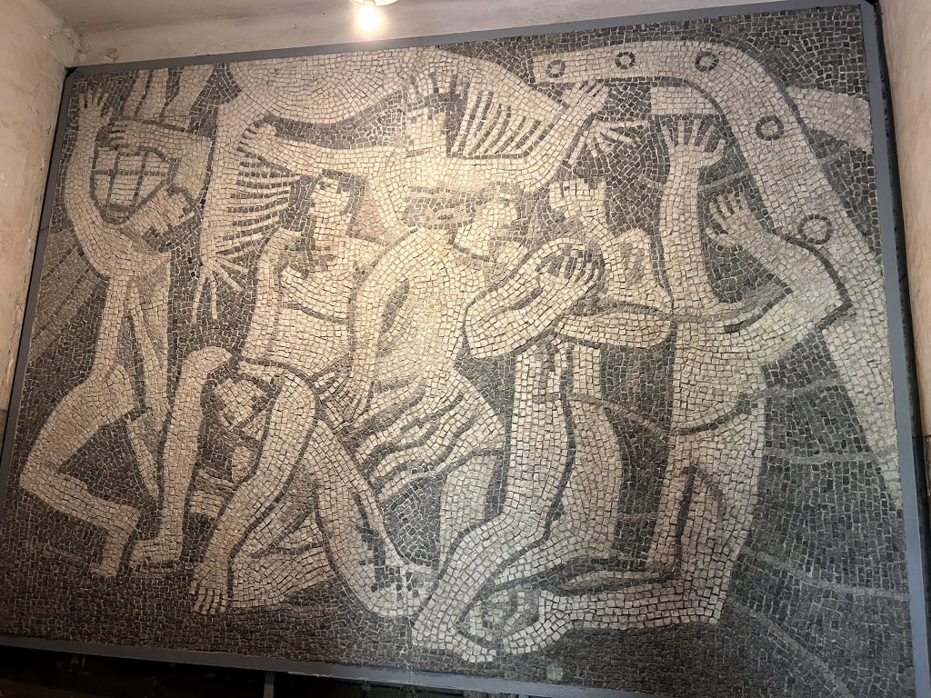 A black and white mosaic depicting abstract human figures engaged in dynamic poses, showcasing movement and emotion.