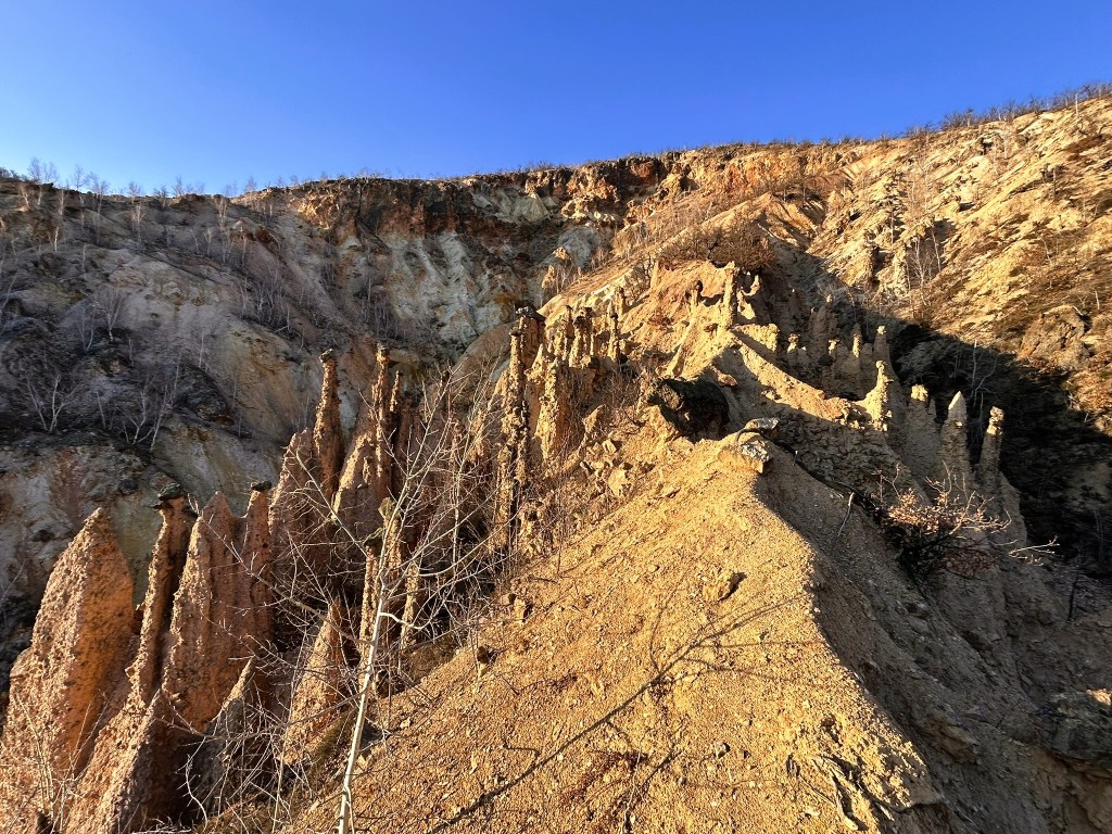 A scenic view of a rocky cliff featuring unique spire-like formations under a clear blue sky.