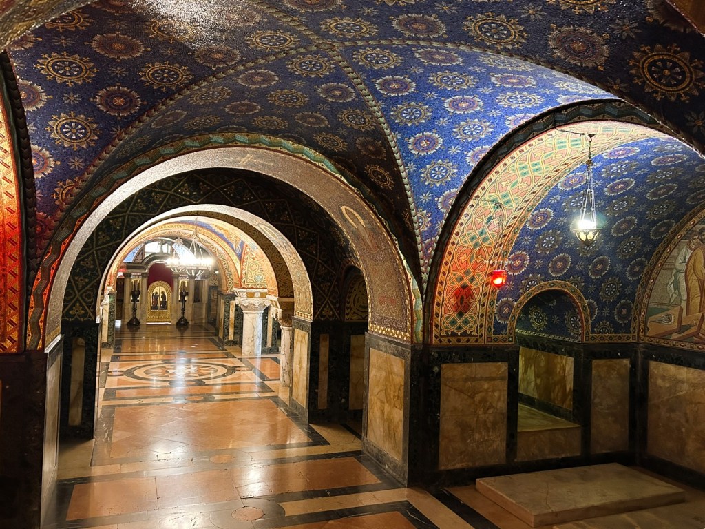 Decorative archway interior featuring intricate blue and red patterned ceilings, elegant marble floors, and soft lighting.