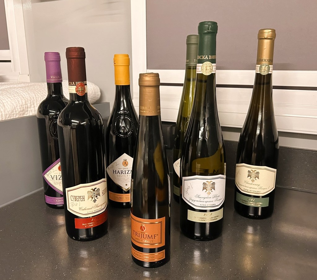 A selection of wine bottles arranged on a dark countertop, featuring various labels and colours, including red, white, and sparkling wines.