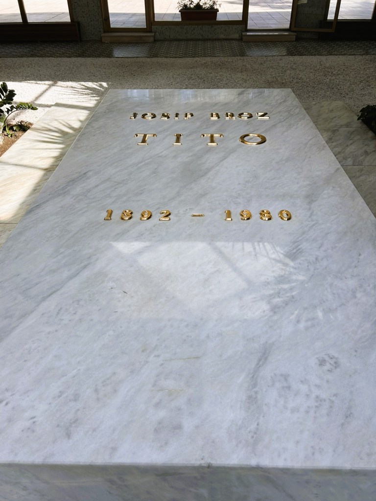 Gravestone of Josip Broz Tito, featuring his name and years of birth and death, 1892 - 1980, engraved in gold letters on a marble slab.