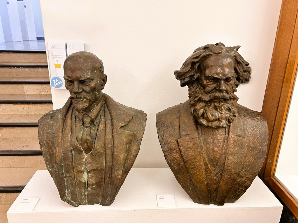 Bronze busts of Vladimir Lenin and Karl Marx displayed side by side in a gallery, highlighting their historical significance.