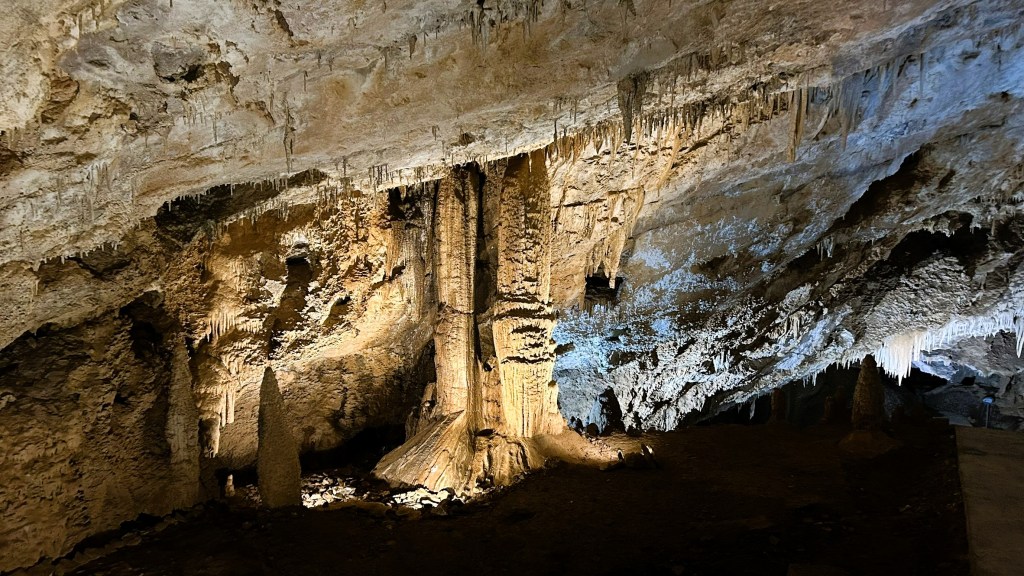 A stunning cave interior featuring stalactites and stalagmites, illuminated by soft lighting, showcasing intricate rock formations and textures.