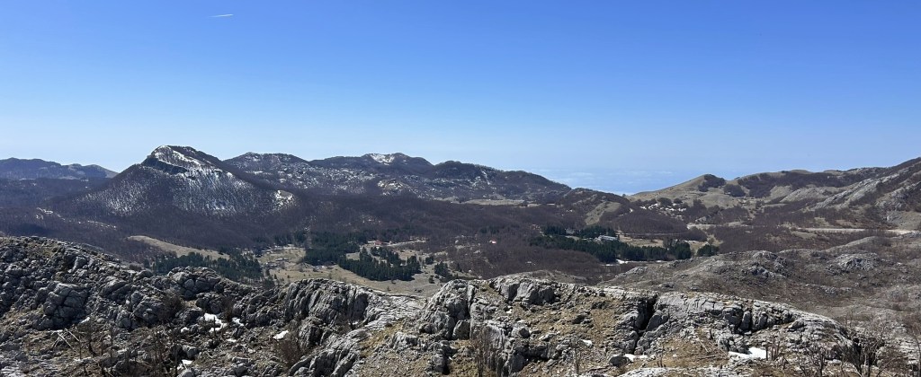 Scenic panoramic view of mountain hills with rocky outcrops under a clear blue sky.